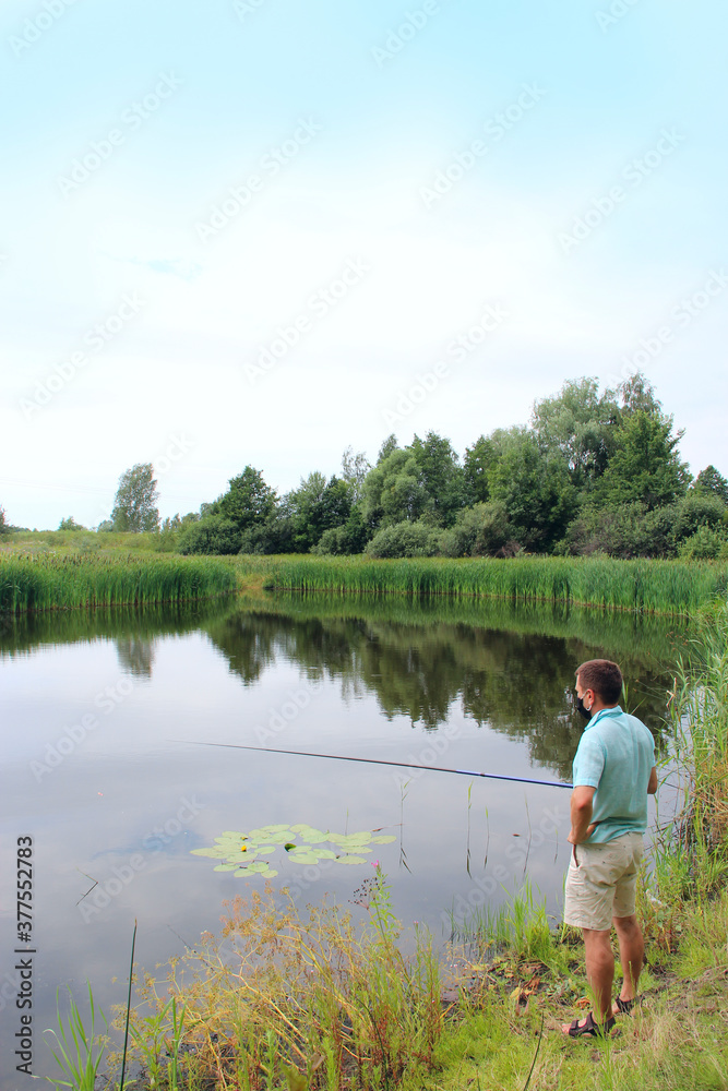 fisherman in protective mask casting fishing rod during quarantine. fisherman in protective mask casting fishing rod during quarantine.