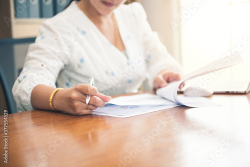 Business woman sitting working and writing to planner event with pen and laptop, computer on table at office or home or internet cafe. Work for safe at home. internet of things communication.