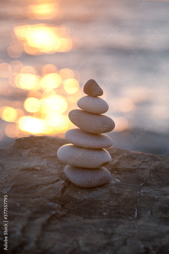 Obraz premium Zen stone pyramid on the seashore in the setting sun