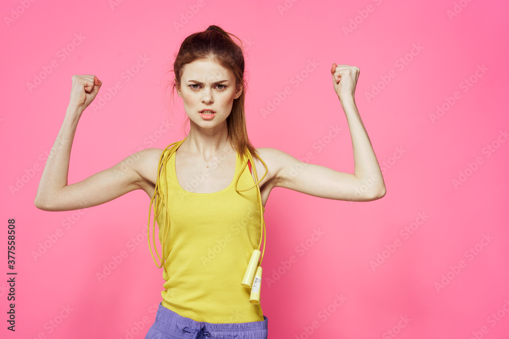 sportive woman jumping rope in hands yellow tank top pink background workout lifestyle