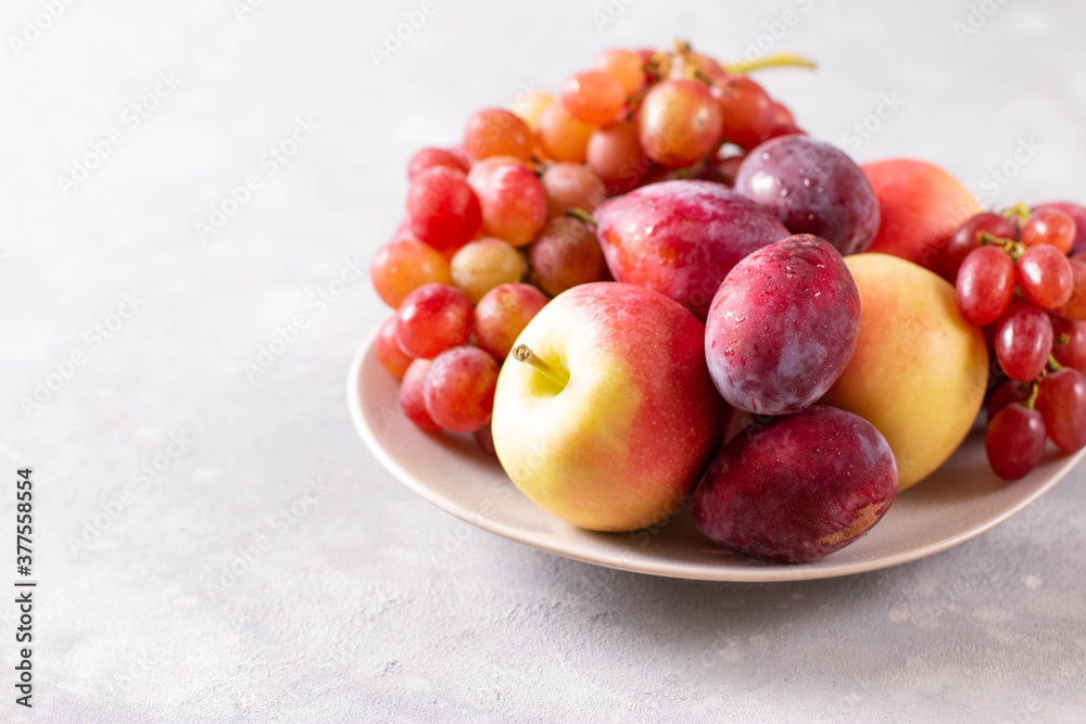 Composition with fruits. Grapes, apples and plums in a plate