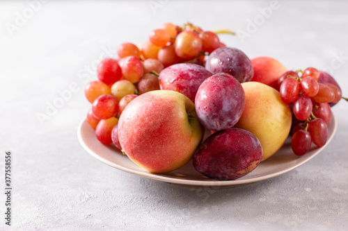 Composition with fruits. Grapes, apples and plums in a plate