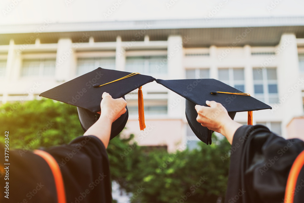 Φωτογραφία Close-up of the hand of the graduate and his friend  Graduation cap on graduatio