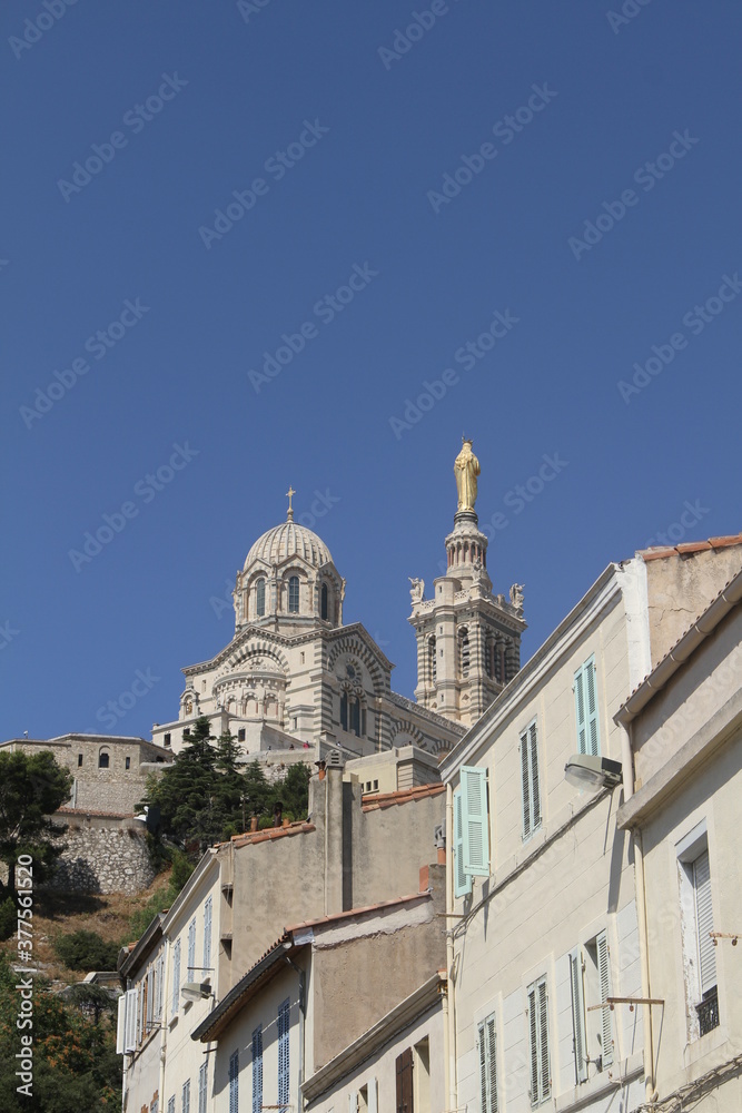 A Marseille, sud de la France, montée vers la basilique Notre-Dame de la Garde, avec des maisons à l'architecture typique de la vieille ville, sur fond de ciel bleu