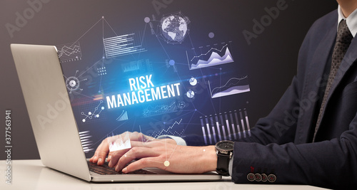 Businessman working on laptop with RISK MANAGEMENT inscription, new business concept