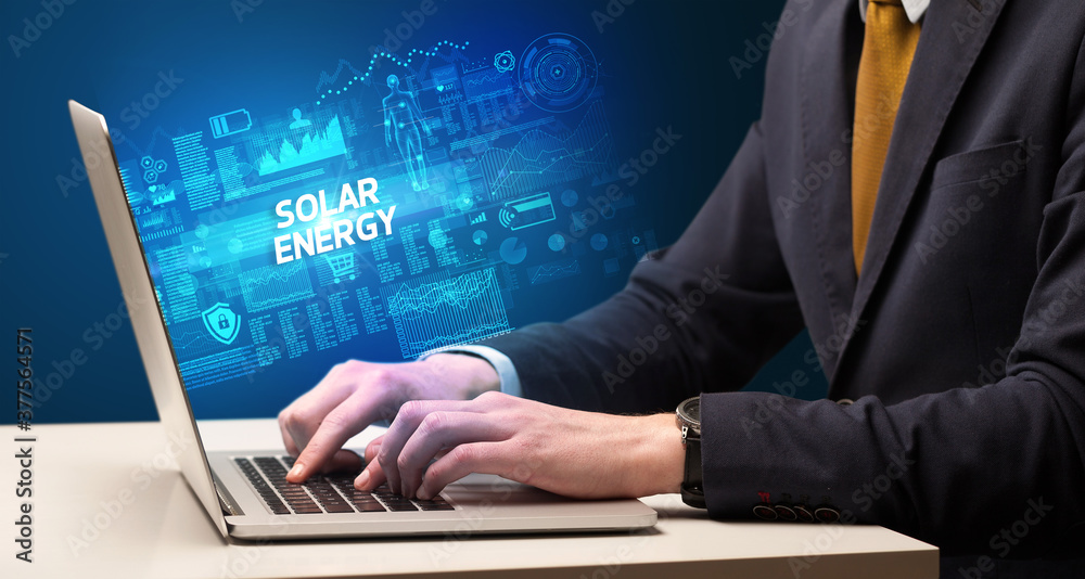 Businessman working on laptop with SOLAR ENERGY inscription, cyber technology concept Businessman working on laptop with SOLAR ENERGY inscription, cyber technology concept