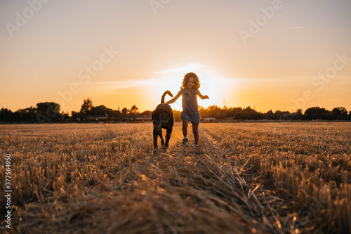Young girl walking accompanied by her dog in the field