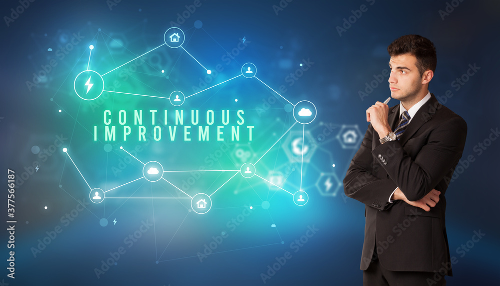Businessman in front of cloud service icons with CONTINUOUS IMPROVEMENT inscription, modern technology concept Businessman in front of cloud service icons with CONTINUOUS IMPROVEMENT inscription, modern technology concept