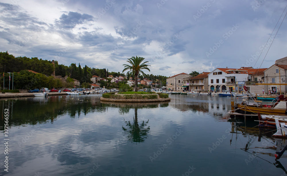 Vrboska/ Croatia-August 7th, 2020: Small, round islet at the end of Vrboska bay with palm tree growing in the center