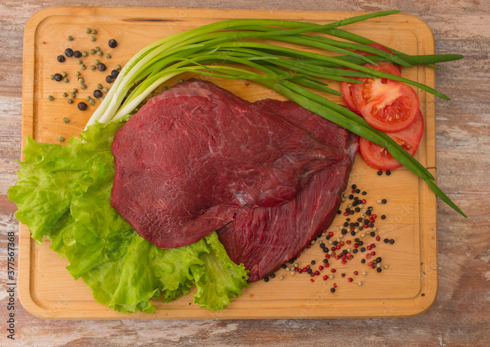 raw beef meat with vegetables on wooden plate. raw beef meat with vegetables on wooden plate.