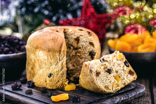 Slice of delicious panettone with candied fruits with blinking blurred Christmas lights, bread with fruits