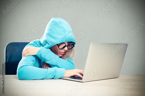 Woman working on a laptop in a hoodie