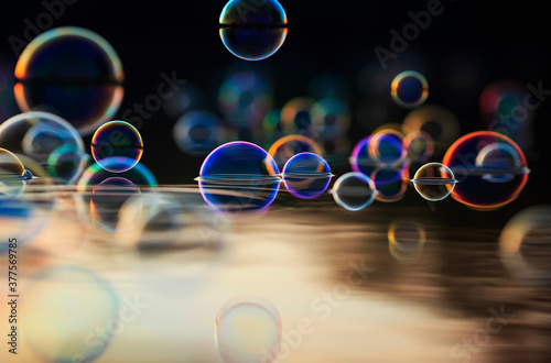beautiful colorful background with shiny soap bubbles flying over the water a...