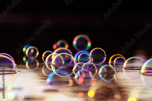 beautiful colorful background with shiny soap bubbles flying over the water a...