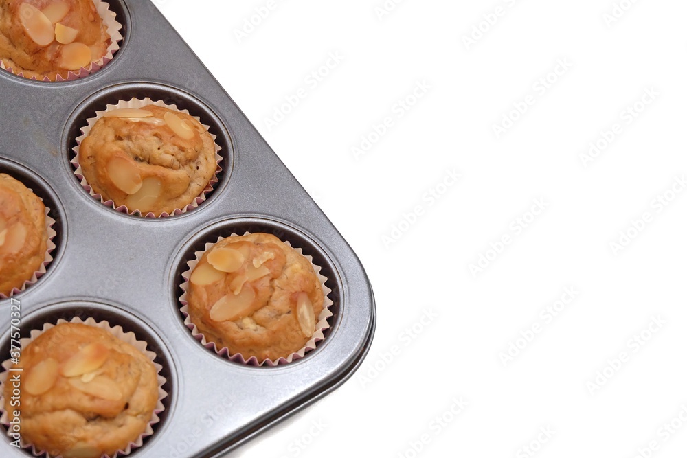 In selective focus homemade banana muffins in a black baking tray with almond sliced on top,on white isolated background with copy space In selective focus homemade banana muffins in a black baking tray with almond sliced on top,on white isolated background with copy space