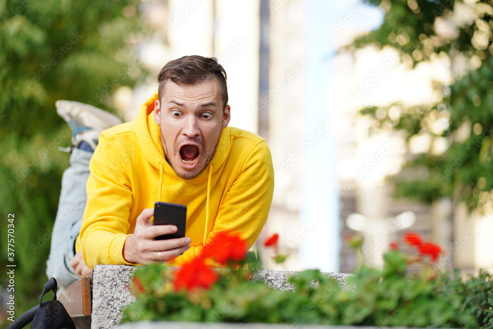 The young man was lying on his stomach outside on a bench with a phone in his hands and in shock at what he saw on the smartphone screen.