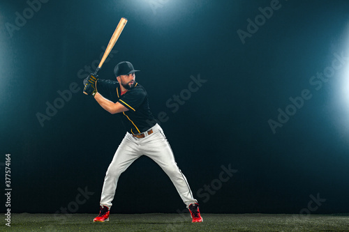 Baseball player with bat on dark background. Ballplayer portrait.