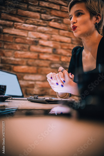 Image of a young attractive businesswoman with a cup of coffee working with her clients in a cafe bar..