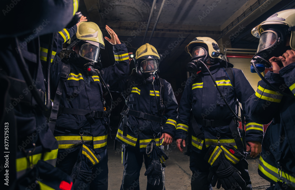 Team of firefighters in the fire department wearing gas masks and uniform Team of firefighters in the fire department wearing gas masks and uniform