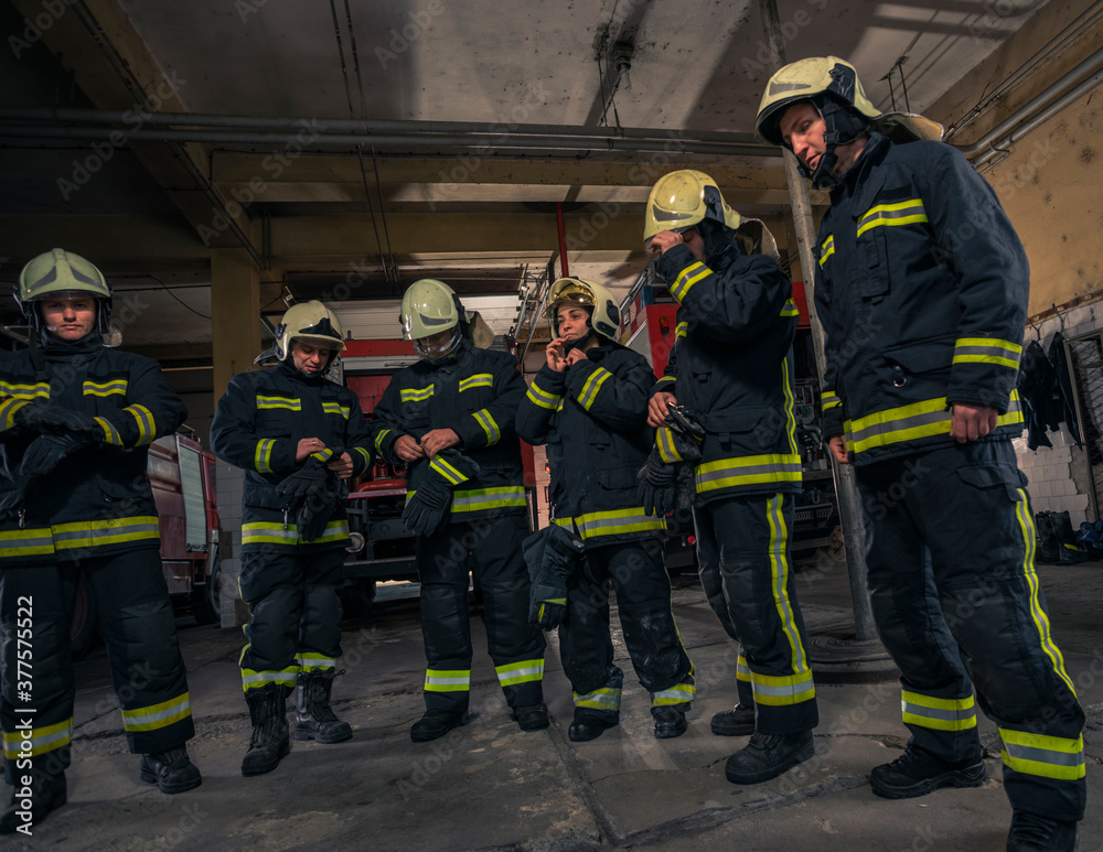 Firemen preparing for emergency service. Firefighters putting on gloves. Firemen preparing for emergency service. Firefighters putting on gloves.