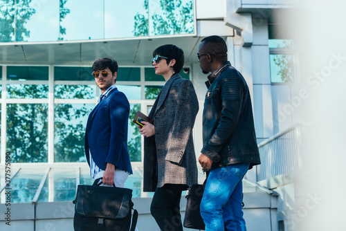 Group of three multi-ethnic business colleagues talking while walking outside on a break photo