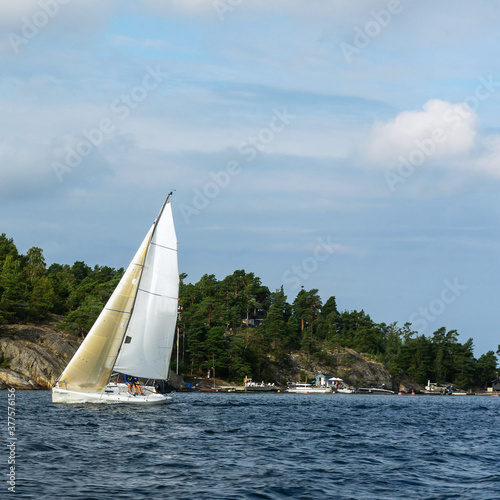 Sailing boat on blue water near the shore.