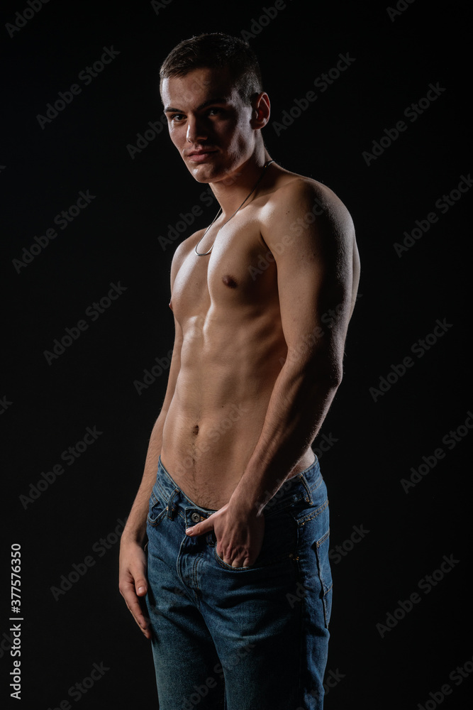 Portrait of a strong healthy handsome athletic man posing as a fitness model on dark background