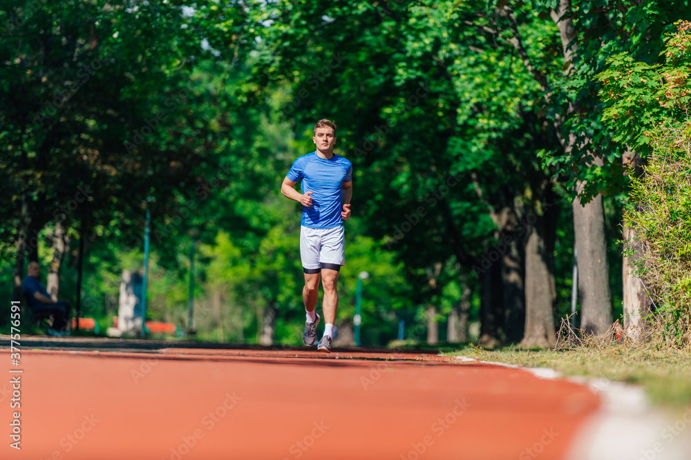 Strong athletic man jogging on the running track