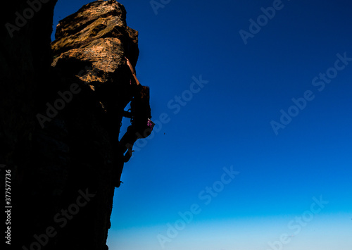 Young woman beginner climbing vertical cliff