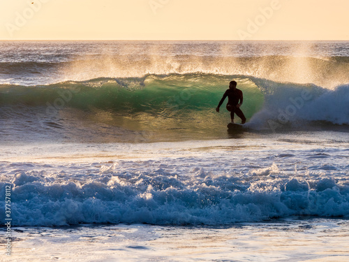 The silhouette of a surfer surfing a wave in Cornwall as the sunsets
