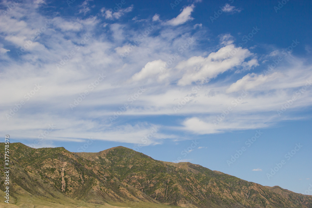 Summer scenery: blue cloudy sky and green hills. Kazakhstan, August