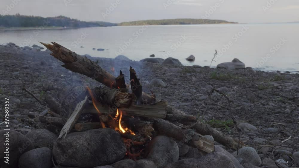 Closeup view bonfire fire in camp on the stone shore lake. Karelia at sunrise Closeup view bonfire fire in camp on the stone shore lake. Karelia at sunrise