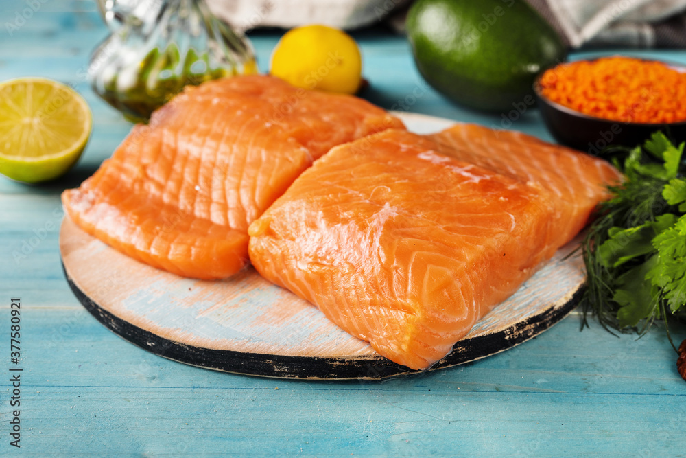 Close up of fresh raw salmon fillet with healthy products on light blue background