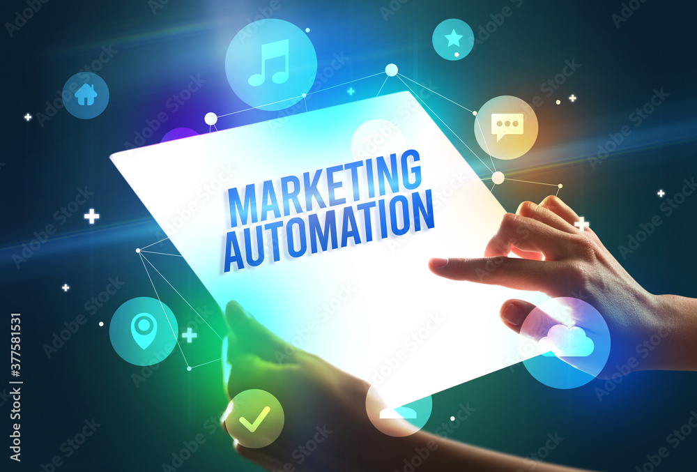 Holding futuristic tablet with MARKETING AUTOMATION inscription, new technology concept Holding futuristic tablet with MARKETING AUTOMATION inscription, new technology concept