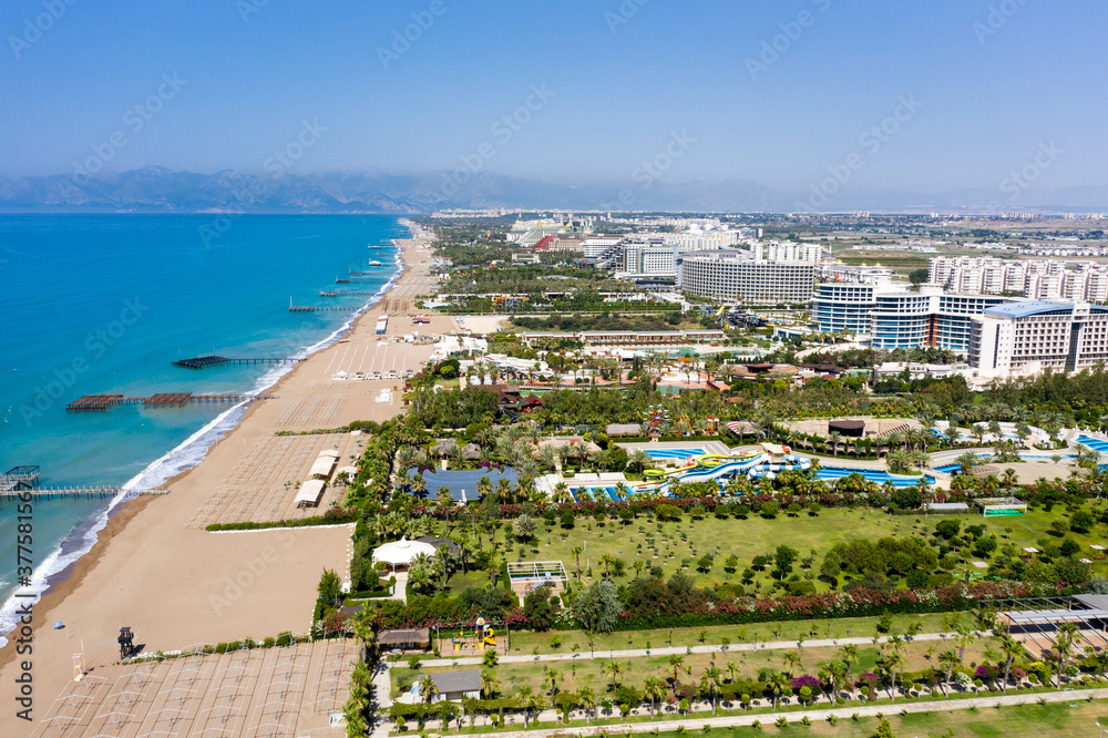 Fototapeta premium Sandy beaches of the Mediterranean. Kundu holiday complex with five star hotels. Beach, sea, water sports, parasailing, entertainment and shopping center. Aerial view with drone. Kundu, Lara -TURKEY