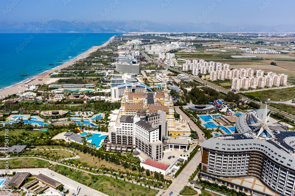 Fototapeta premium Sandy beaches of the Mediterranean. Kundu holiday complex with five star hotels. Beach, sea, water sports, parasailing, entertainment and shopping center. Aerial view with drone. Kundu, Lara -TURKEY