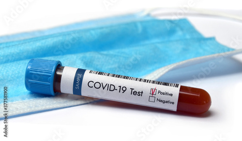 Coronavirus test blood sample positive result in test-tube.with face mask in the background