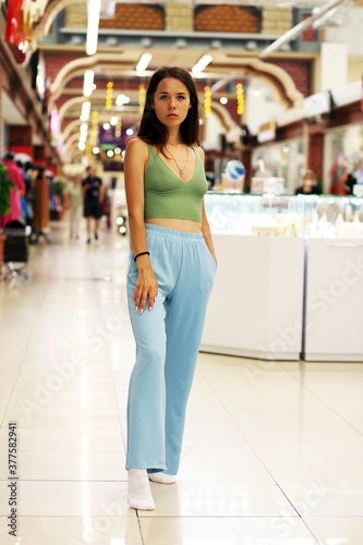 young woman in green top and blue pants at the mall