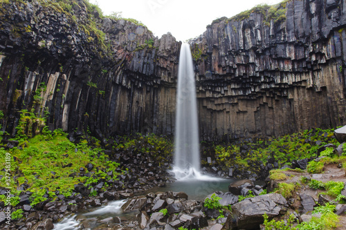 small waterfall in the middle of basalt rock columns 