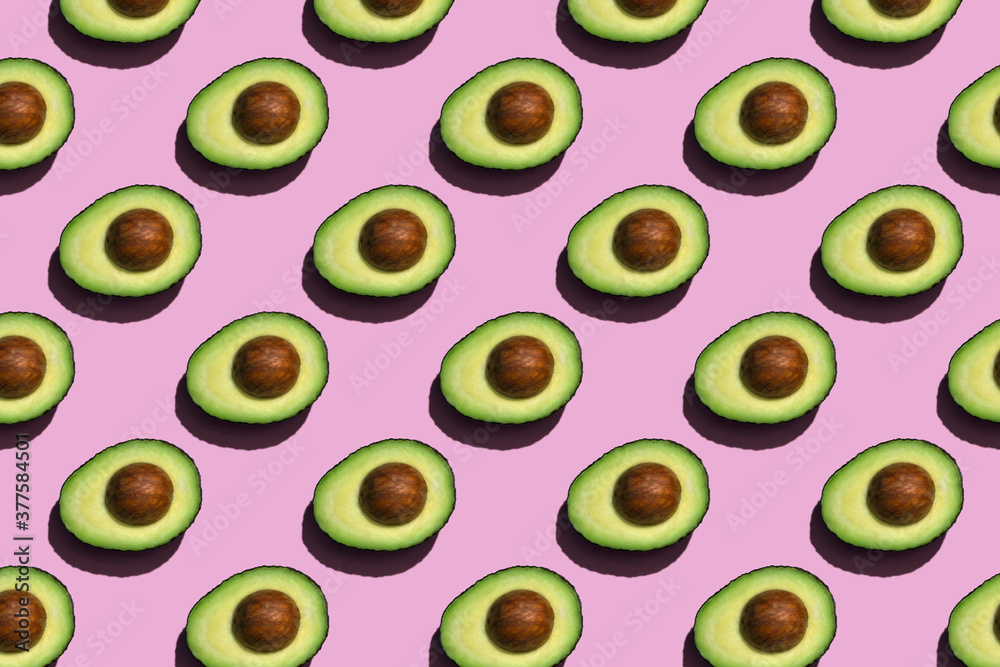 Avocado pattern on pink or lilac background. Half avocado background with seed. Avocado pattern on pink or lilac background. Half avocado background with seed.