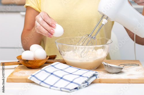 making dough for bread or homemade baked goods. ingredients on the desk. female hands holding an egg