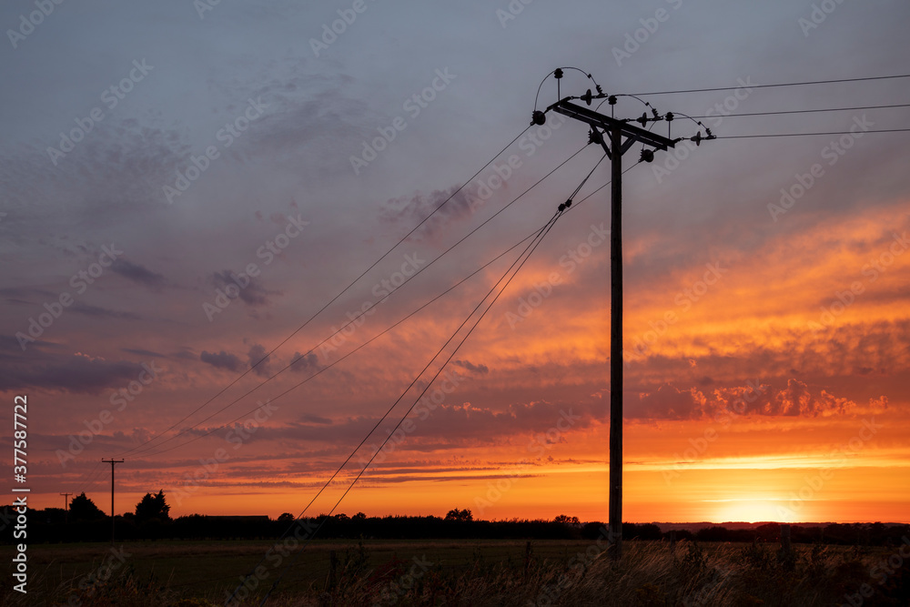 Dystopian, orange hellish sky with isolated power line, depicting global warming, pollution, and the damaging effects of burning fossil fuels for electricity to our environment.