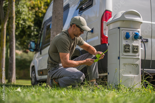 Men Attaching Electric Plug to RV Park Hookup photo