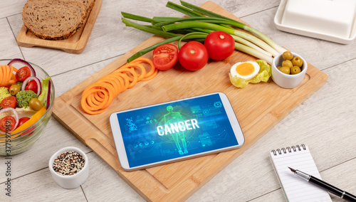 CANCER concept in tablet with fruits, top view