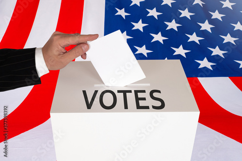A hand drops a ballot into ...