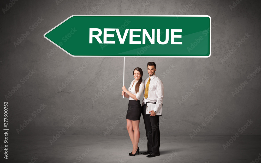 Young business person in casual holding road sign with REVENUE inscription, new business direction concept Young business person in casual holding road sign with REVENUE inscription, new business direction concept