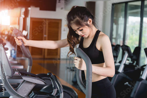 Young woman lifestyle using machine elliptical for cardio workout at fitness gym