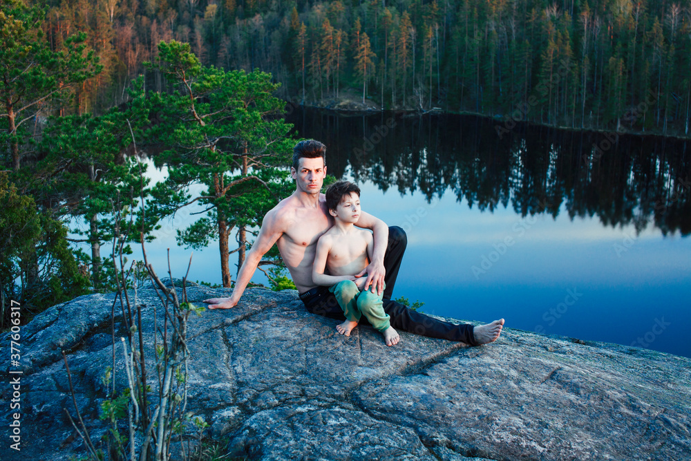 middle age man with little cute son doing sport yoga on the top of the mountain together, happy family lifestyle people outdoor, summer wild nature for training middle age man with little cute son doing sport yoga on the top of the mountain together, happy family lifestyle people outdoor, summer wild nature for training