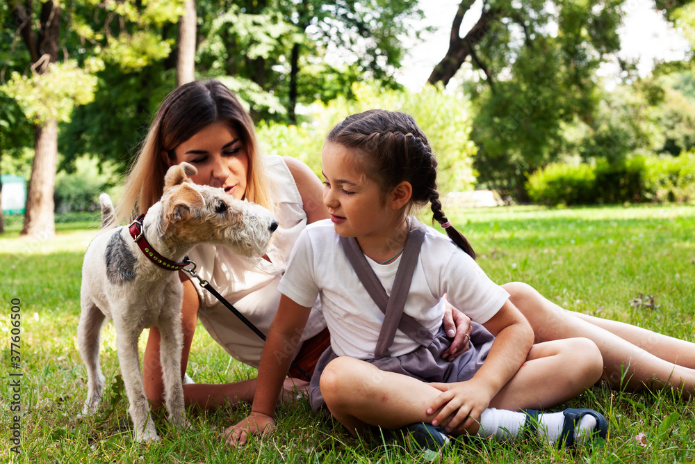 Obraz premium young pretty caucasian mother walking with little cute daughter and dog fox terrier, lifestyle people concept