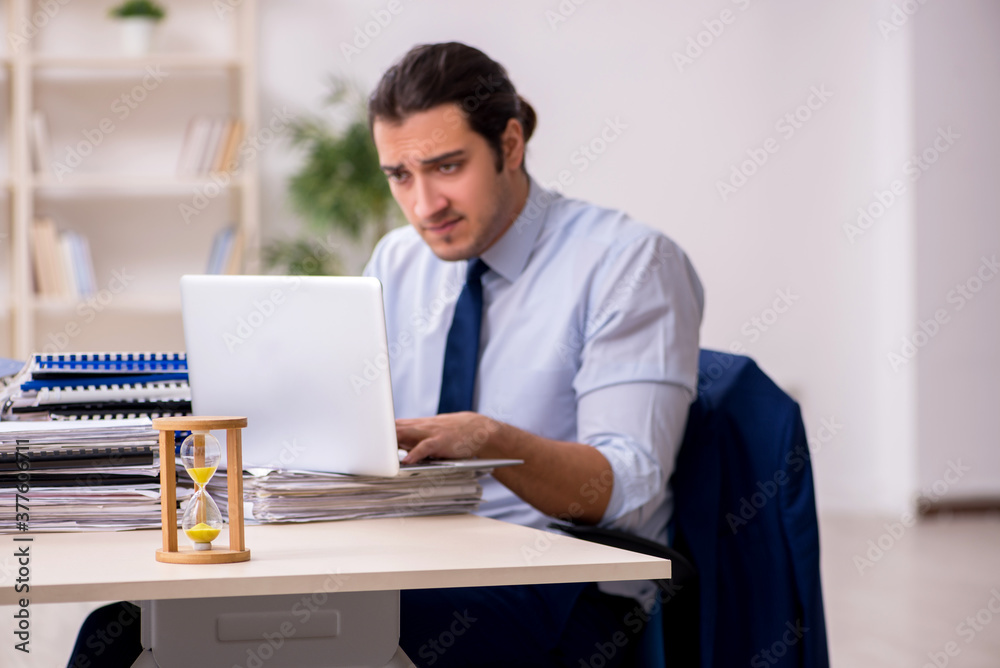 Young male employee in time management concept Young male employee in time management concept